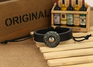 Close-up of vintage black leather bracelet featuring sunburst etched bronze metal buckle
