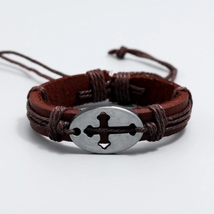 Macro di un bracciale in pelle intrecciata con placca in metallo a croce vintage