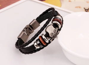 Detail of multilayer leather bracelet with a retro skull charm and vintage metal beads