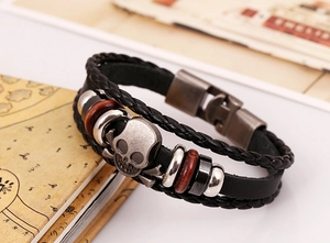 Macro detail of multilayer leather bracelet featuring a silver skull and vintage beads