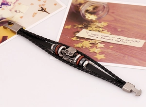 Detail of punk leather bracelet featuring a vintage metal skull and woven bands