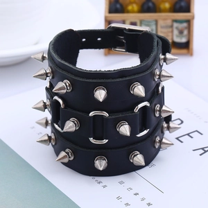 Détail du bracelet punk en cuir noir orné de trois rangées de pointes métalliques argent
