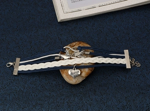 Detail of woven multi-layer bracelet with heart sister charm and infinity metal symbol