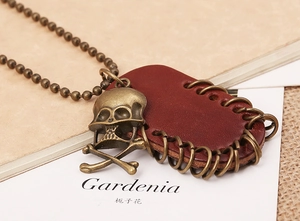 Macro shot of bronze skull pendant and brown leather with metallic rings on bead chain