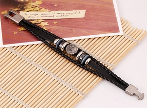 Detail of vintage braided leather bracelet with metal gear charm on a bamboo mat