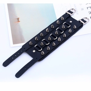 Détail du bracelet punk en cuir noir orné de trois rangées de pointes métalliques argentées