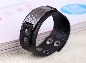 Detailed macro view of black leather bracelet featuring hammered silver metal plate decor