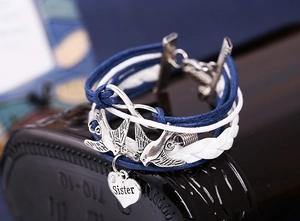 Detail of multi-layer braided bracelet with silver infinity symbol and sister heart charm