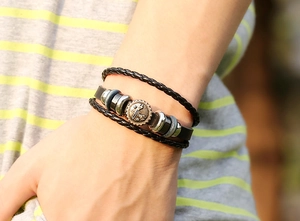 Detail shot of men's multi-layer leather bracelet with bronze medallion on wrist