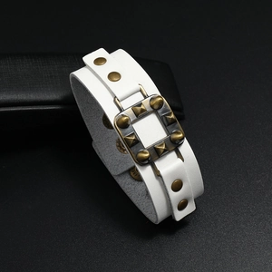 Detailaufnahme eines weißen Punk-Lederarmbands mit Bronze-Nieten und Metallschnalle