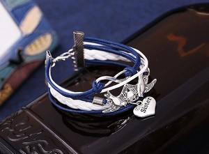Macro detail of bohemian braided bracelet with silver bird charm and Sister heart pendant