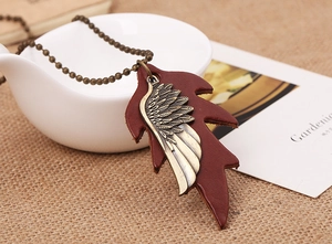 Detailed close-up of bronze metal feather pendant on leather leaf with a ball chain necklace