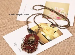 Detail of 62cm bronze ball chain with skull and crossbones leather pendant on burlap