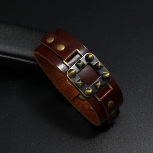 Detail eines Vintage-Lederarmbands in Rotbraun mit Bronzenieten und Punk-Metallschnalle