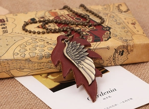 Macro view of vintage bronze feather and brown leather leaf pendant with beaded metal chain