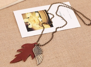 Detail of vintage wing and leather maple leaf pendants on a retro beaded necklace chain