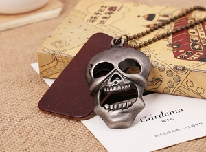 Détail d'un pendentif crâne style punk argent vieilli sur une chaîne à billes bronze