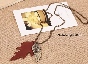 Detail of vintage wing and leaf pendant on long bronze bead chain over burlap