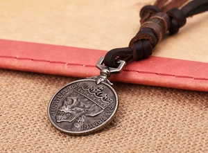 Détail macro du pendentif pièce vintage avec relief tête de mort sur collier en cuir tressé