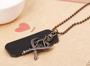 Detail of bronze pirate skull and cross swords pendant on black leather backing