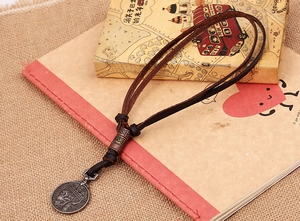 Vue détaillée du pendentif crâne rétro sur cordon en cuir marron avec perles en métal