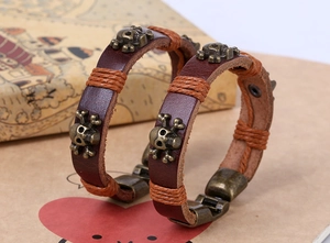 Close-up of punk leather bracelet with bronze skull rivets and orange rope details