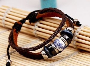 Détail d'un bracelet vintage en cuir tressé avec perle en porcelaine à motif floral bleu