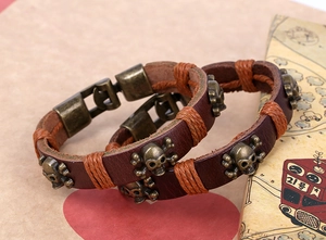Macro view of two-piece punk leather bracelets featuring bronze skull charms on retro paper