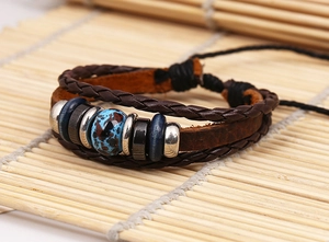Detailed macro view of vintage multi-layer braided leather bracelet with central patterned bead