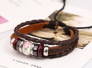Detail of vintage braided leather bracelet with floral ceramic bead and wooden accents
