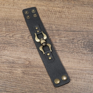 Detail of black punk PU leather bracelet featuring bronze studs and a vintage bull head emblem