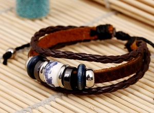 Détail macro d'un bracelet en cuir tressé vintage avec perle céramique et entretoises