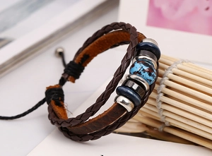 Detail of vintage braided brown leather bracelet with blue ink-patterned bead and metal rings