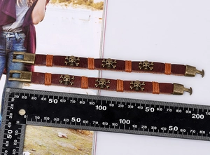 Detail view of two punk leather bracelets with bronze skull studs and orange string accents