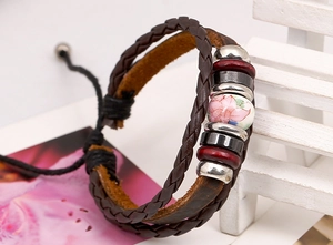 Detail of multilayer woven leather bracelet featuring floral ceramic bead and metal accents
