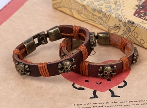 Macro detail of retro leather bracelets with bronze skull charms and woven rope accents