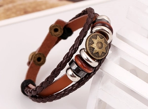 Detail view of multi-layer brown leather bracelet with star-etched gold medallion and beads