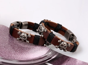 Close-up of vintage brown leather punk bracelet with silver skull charms and metal clasp