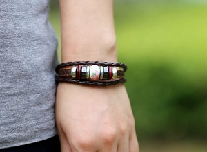 Detail of vintage multilayer leather bracelet with lotus ceramic bead on wrist