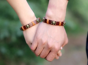 Close-up of retro skull leather bracelets on a couple holding hands in a park