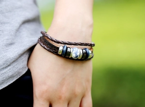 Détail d'un bracelet multicouche en cuir tressé marron avec perles en céramique et métal poli