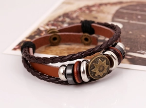 Detail of vintage leather bracelet with braided cords and bronze star charm engraving
