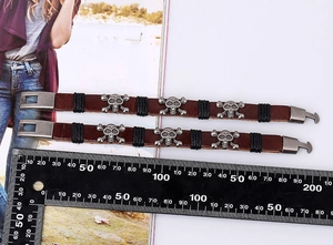 Detail of vintage punk leather bracelets with silver skull charms and metal buckle
