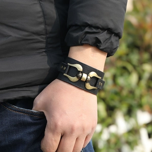 Close-up of a men's wide black punk leather bracelet with vintage brass metal hooks
