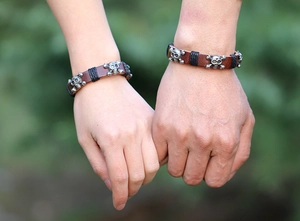 Detail of couple wearing vintage skull leather bracelets with woven rope and silver charms