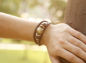 Detail of vintage braided leather bracelet with golden star charm and wood beads