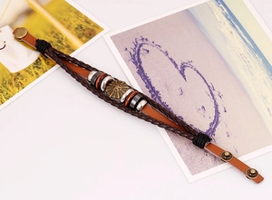 Detail of vintage multilayer leather bracelet featuring a sunburst metal plate and wooden beads