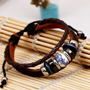 Bracelet vintage en cuir tressé avec perles de céramique bleue sur un tapis de bambou