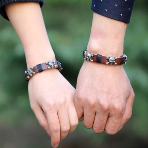 Vintage punk leather bracelets with silver skull charms on a person's wrist