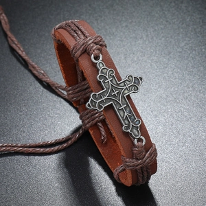 Macro shot of retro braided leather bracelet with vintage engraved alloy cross charm